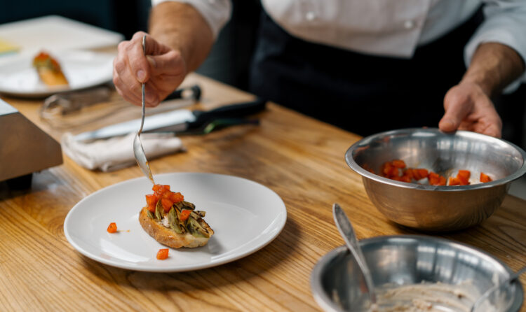 A professional chef puts roasted avocado and tomatoes on toast with spice pouring sauce over them healthy breakfast