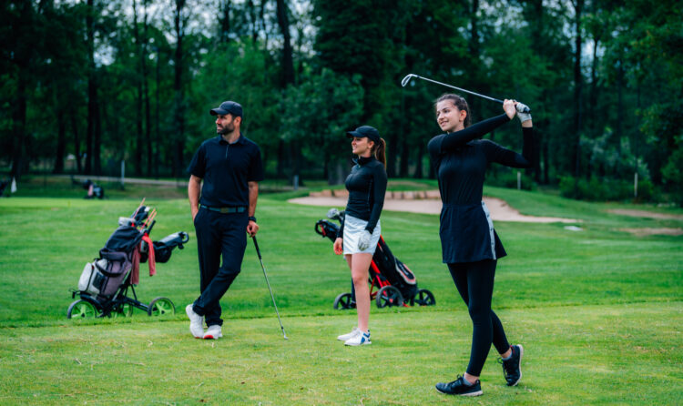 Playing golf. Young woman playing golf with golf instructor